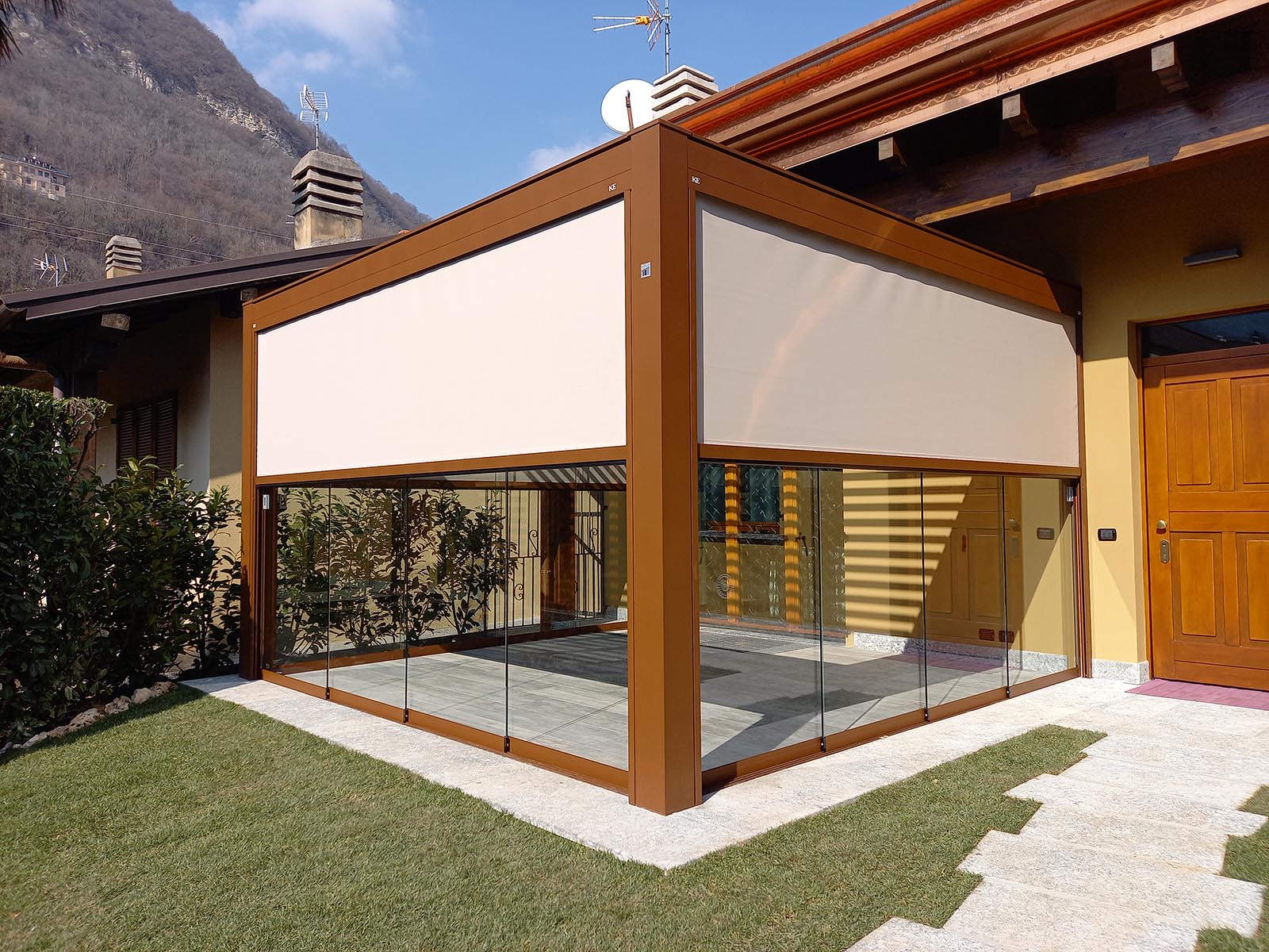 Pergola bioclimatica addossata installata in abitazione con chiusure vetrate laterali